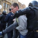 полицейский хватает демонстранта сзади